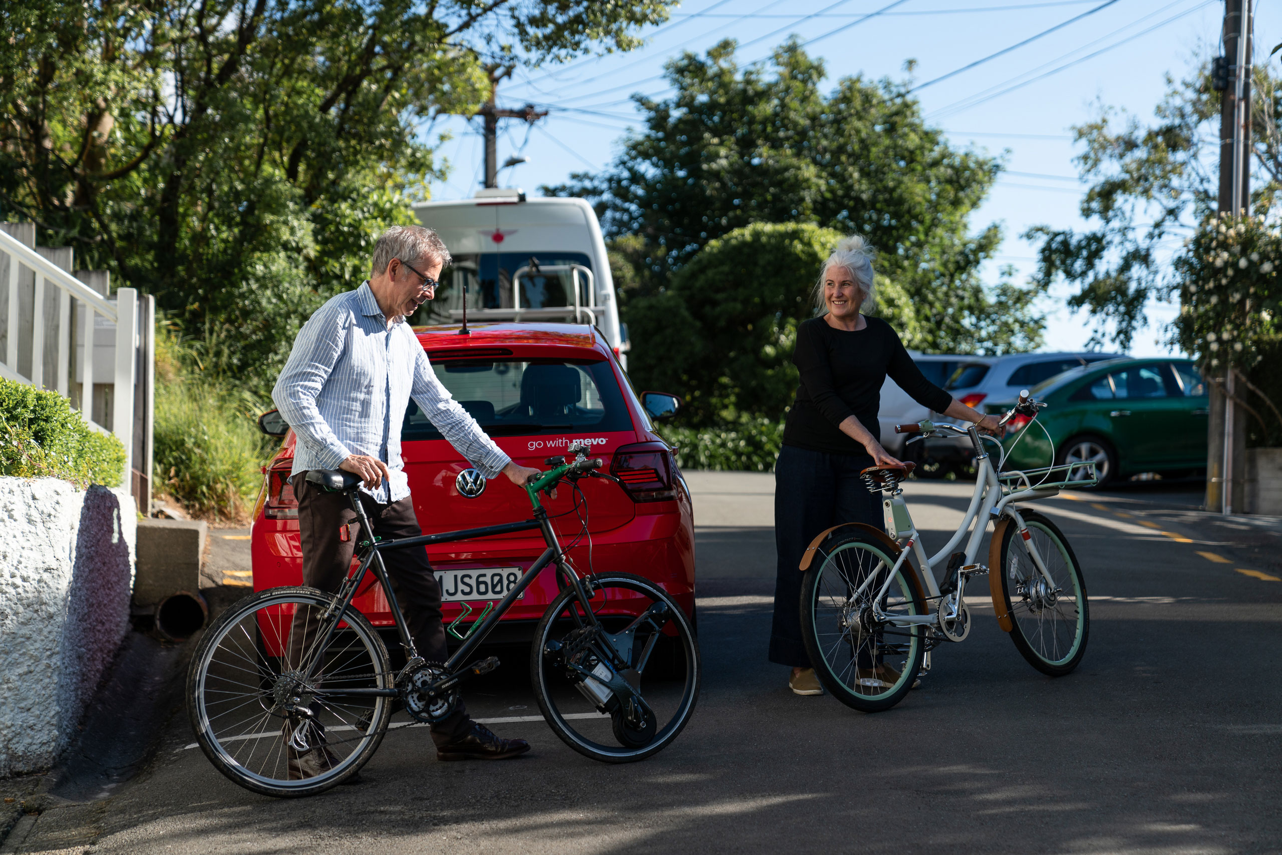 Anne and Chris wheeling their electric bikes across the street.