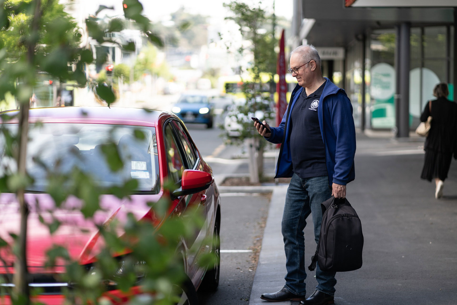 Donald standing next to a Mevo car, unlocking it with his phone.